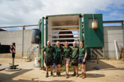 Two male and three female keepers stand in front of a green crate with African Elephant Shaka ready to move