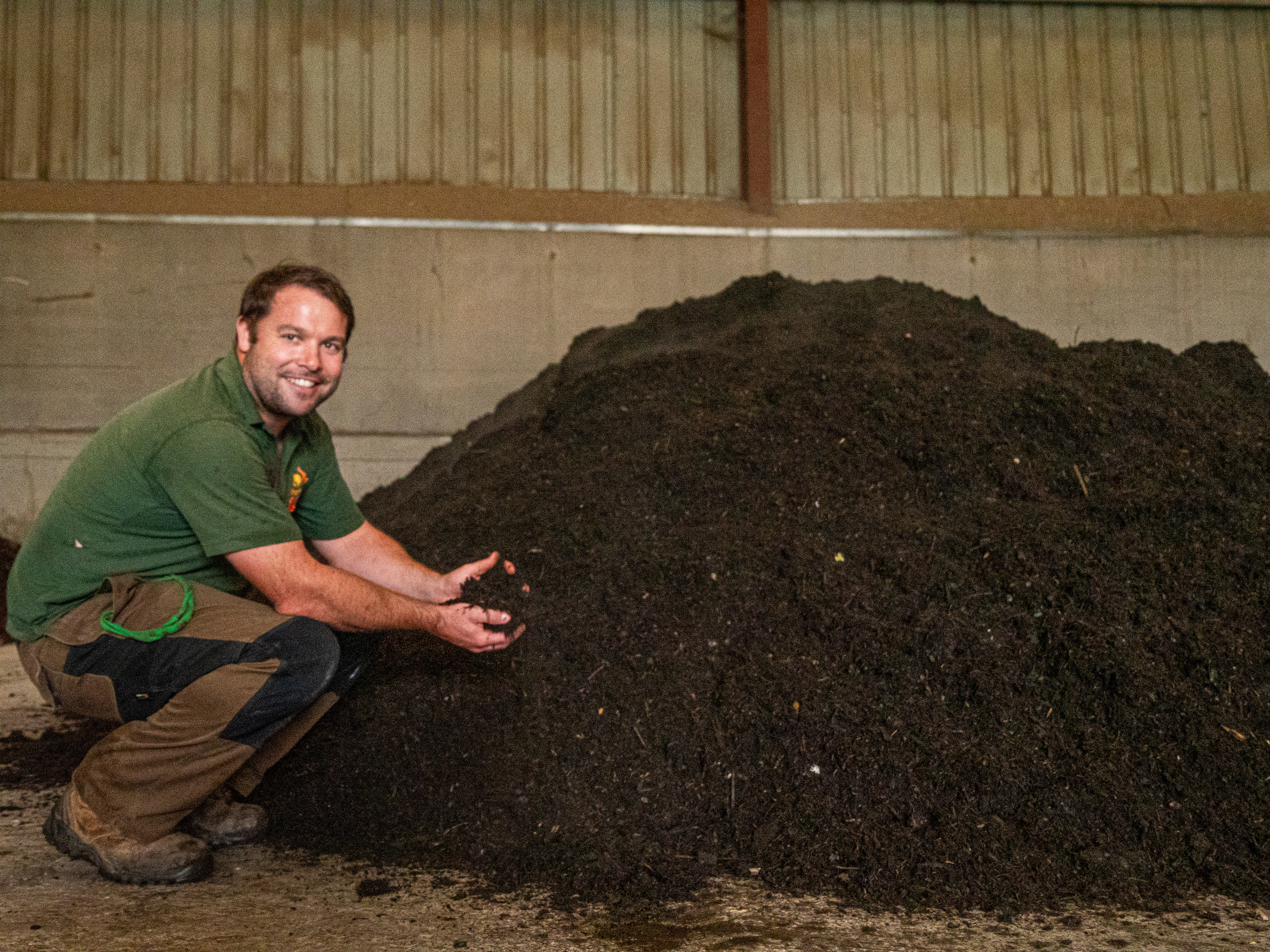 Man holding a hand full of freshly delivered compost 