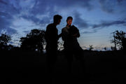 Two male staff members observe bat monitoring technology in the dark.