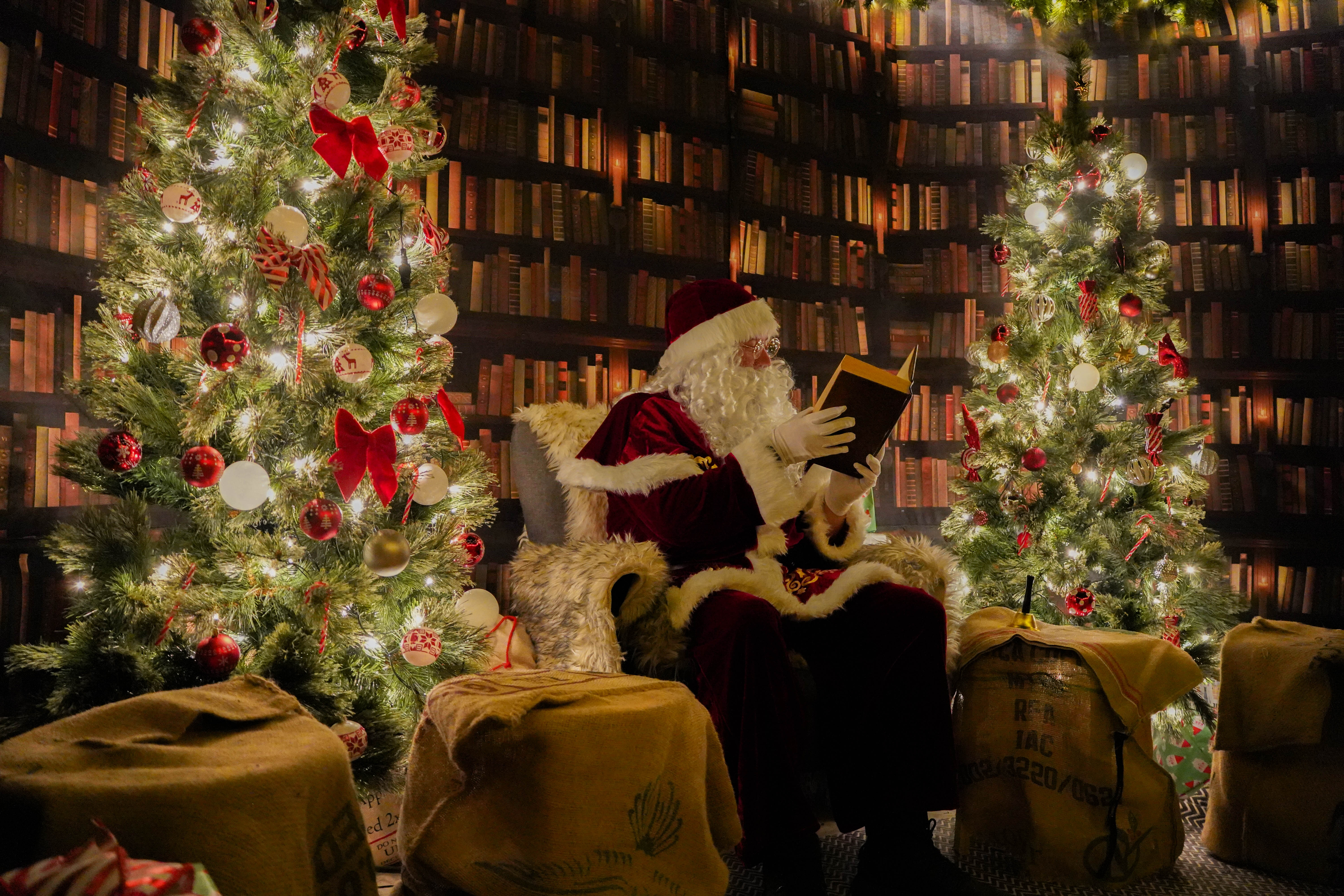 Santa sat in a chair reading a book in his Christmas Library