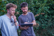 Two male staff members observe IPad while monitoring bats.
