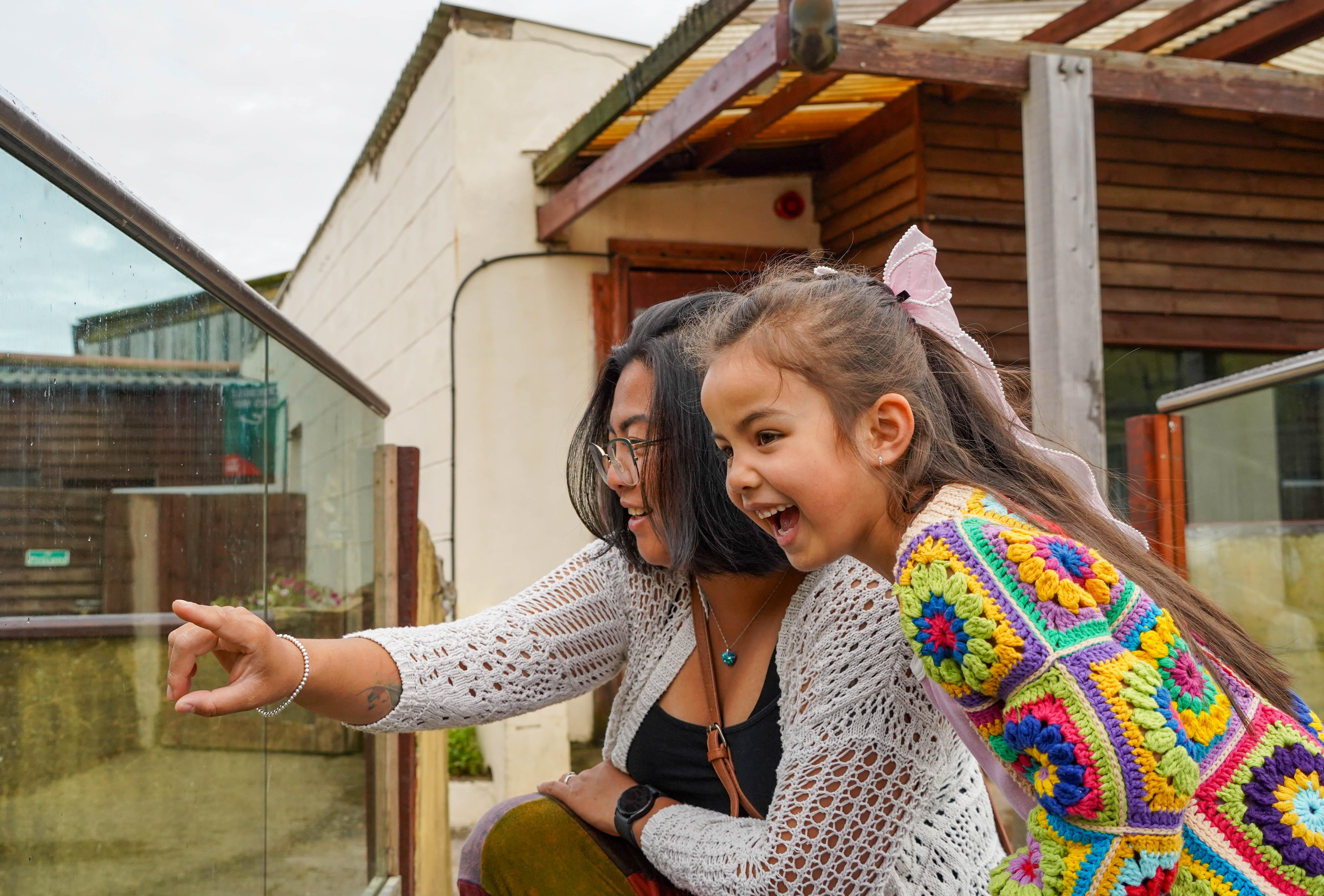 Mum and smiling daughter pointing into an enclosure. 