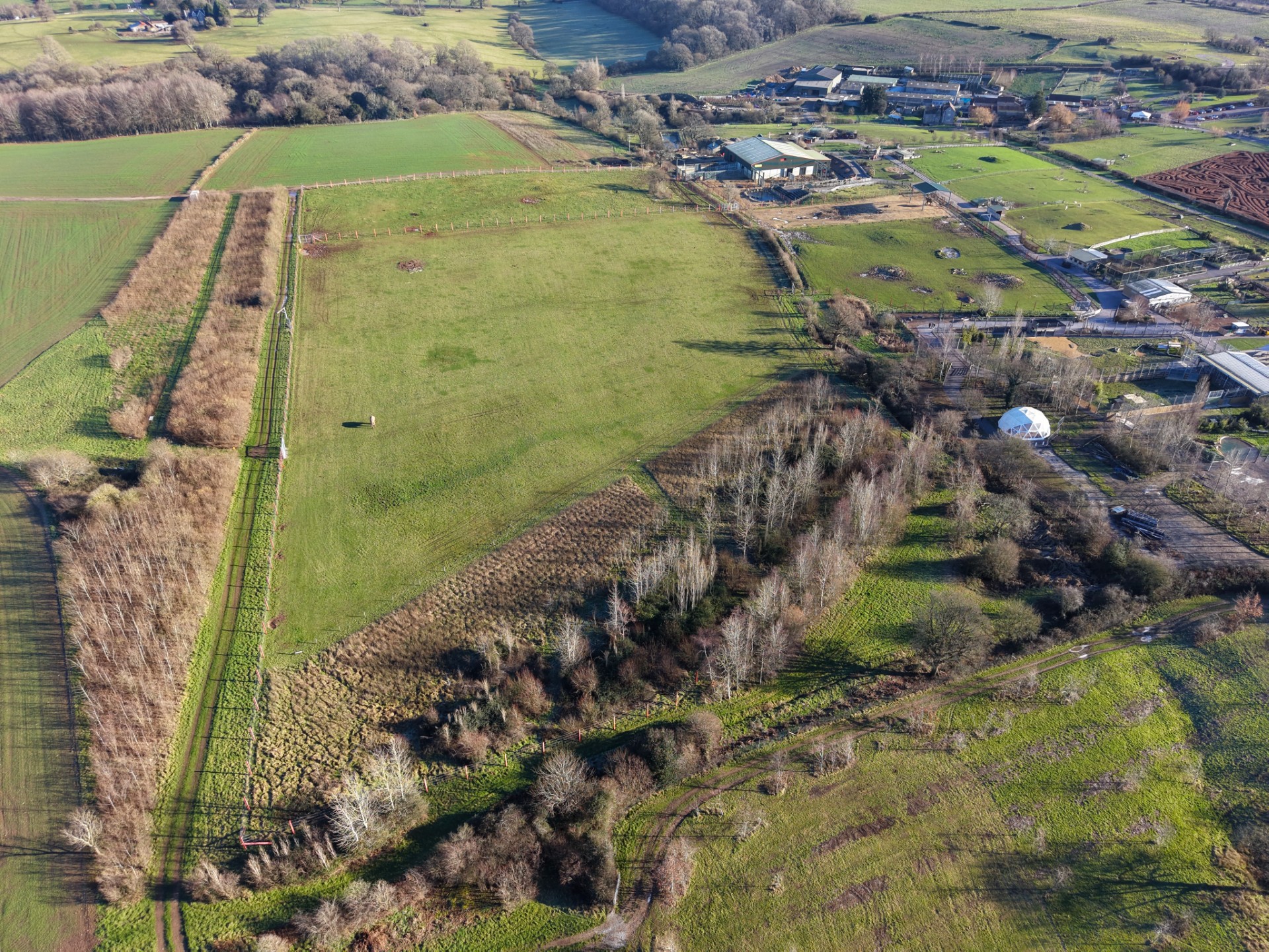 Drone aerial view of Elephant Eden, including the willow plantation, green fields,  elephant house, and surrounding habitats in the Zoo.