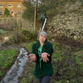 Female keeper holding two hands out with palms covered in mud, standing in moat.