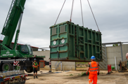 A green crane holding a green crate in the air. The crate holds African Elephant Shaka ready to move to Howletts Zoo. 