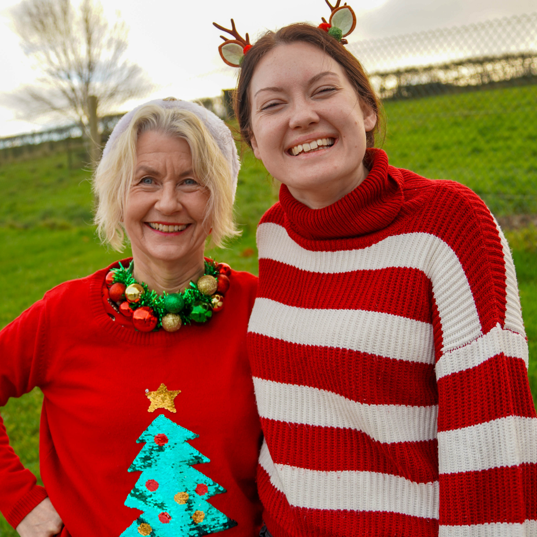 Two female office staff members pose for a photograph on Christmas Jumper day
